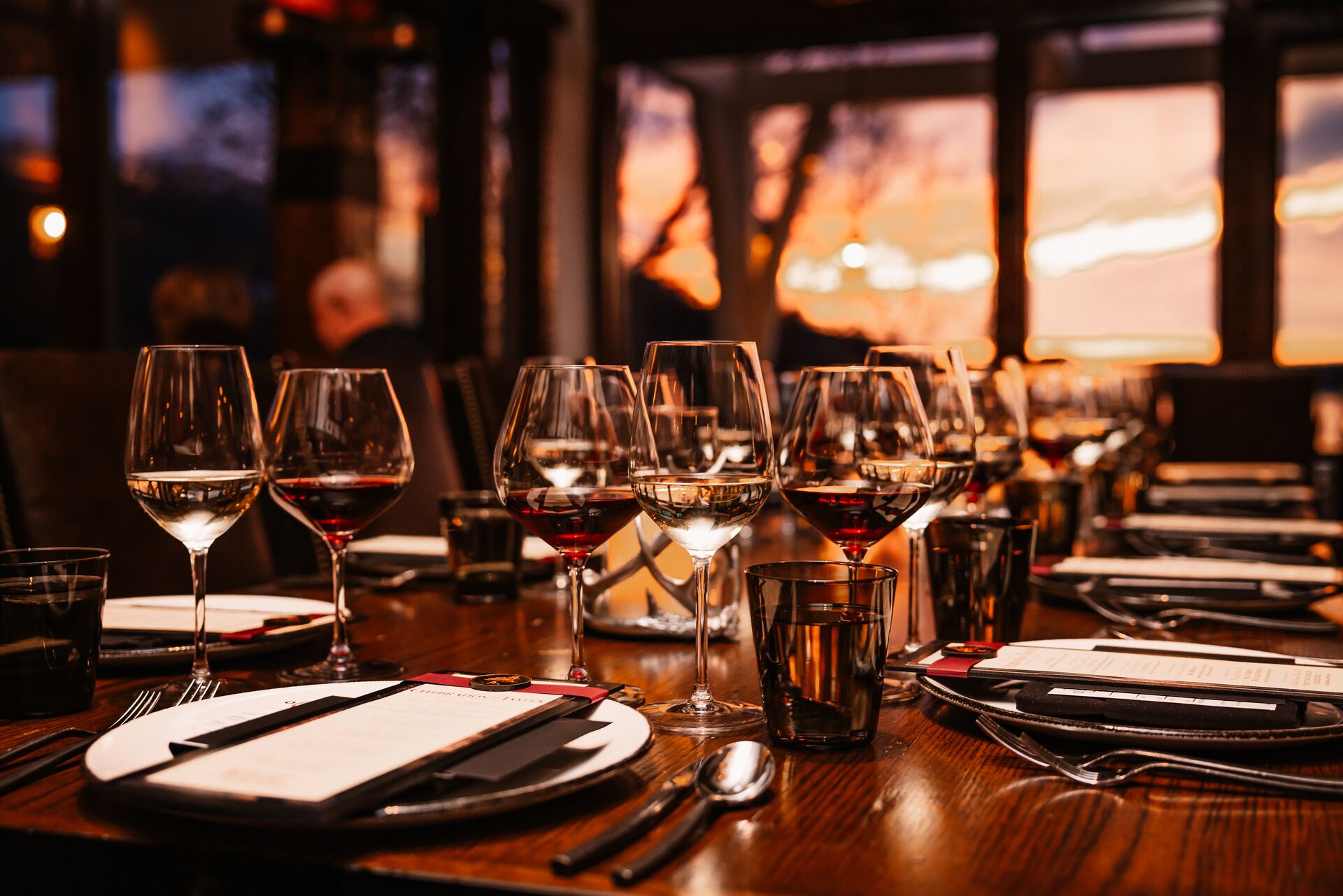 Place setting with wine glasses and sunset in the background