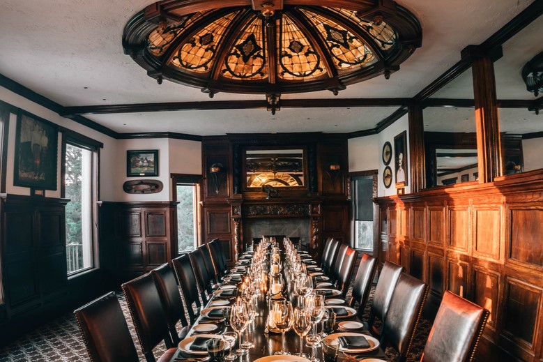 Dining table lined with leather chairs and place settings