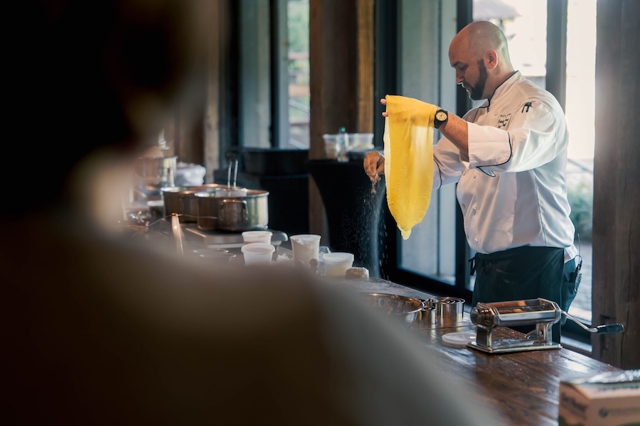 A chef draps a sheet of fresh pasta dough over his hand as he teaches a class