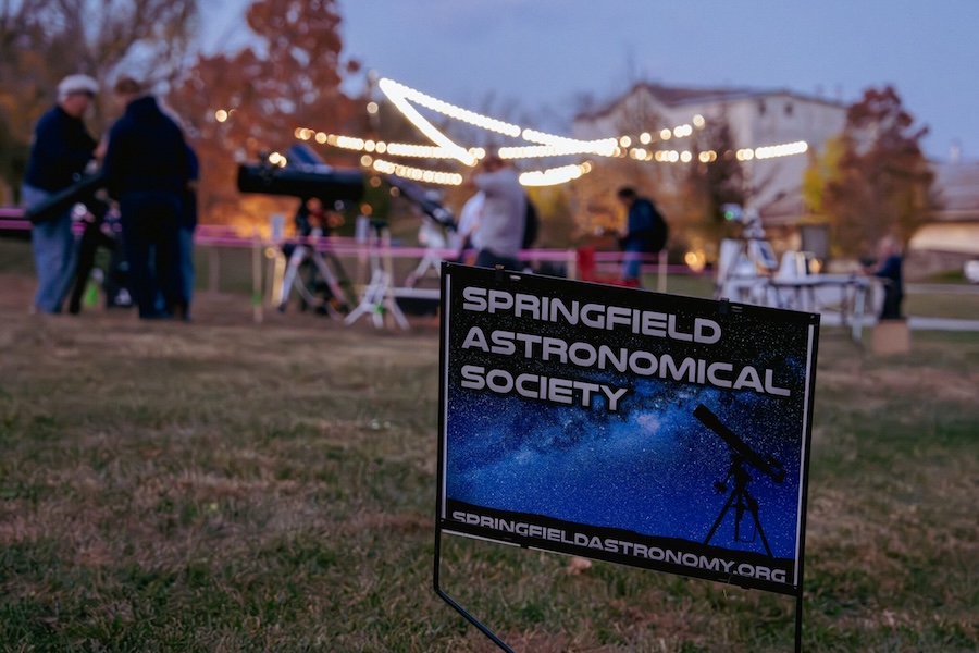 A festival takes place at night with a sign that reads Springfield Astronomical Society