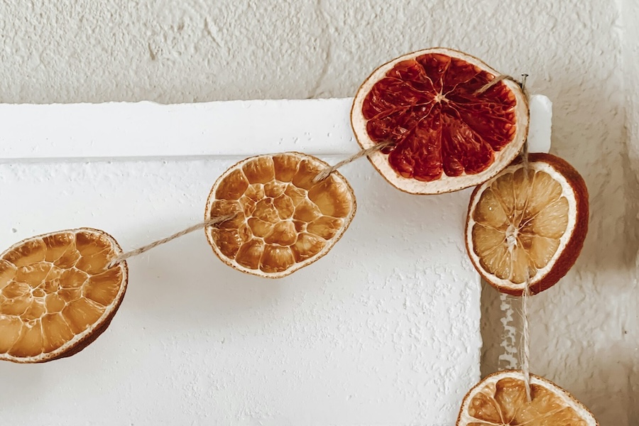 A garland of dried citrus, sliced and hung on hemp twine is hung on a door